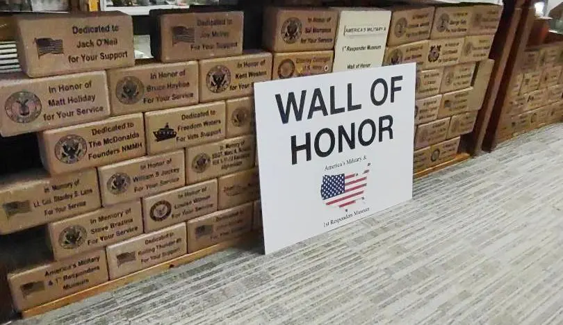 Rows of engraved memorial pavers stacked beneath a Wall of Honor sign
