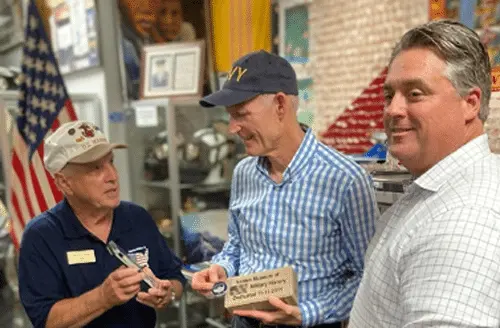 Dave Hinds, President and Matt Holliday, BOD presenting hand carved Navy pen and paver to Rick Scott