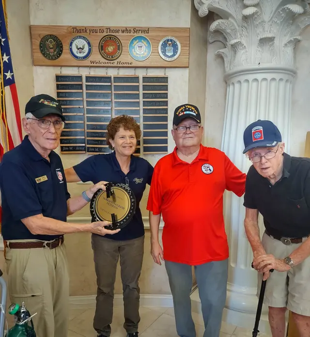 Dedication to Terracina Senior Living Wall of Honor. Left to Right: Joel Banow, docent, presenting Bearing Circle plaque to Leigh, George and John