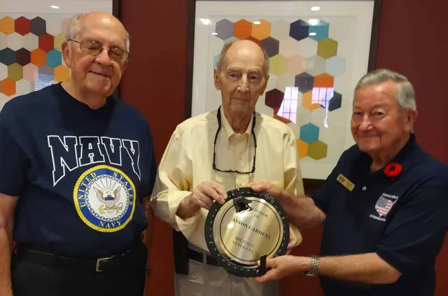 Ralph and Jim, residents of Aston Gardens Naples receiving plaquefrom docent John Green
